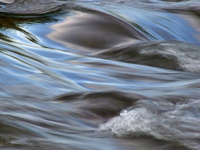 Flowing water with the reflection of the blue sky taken with a slow shutter speed